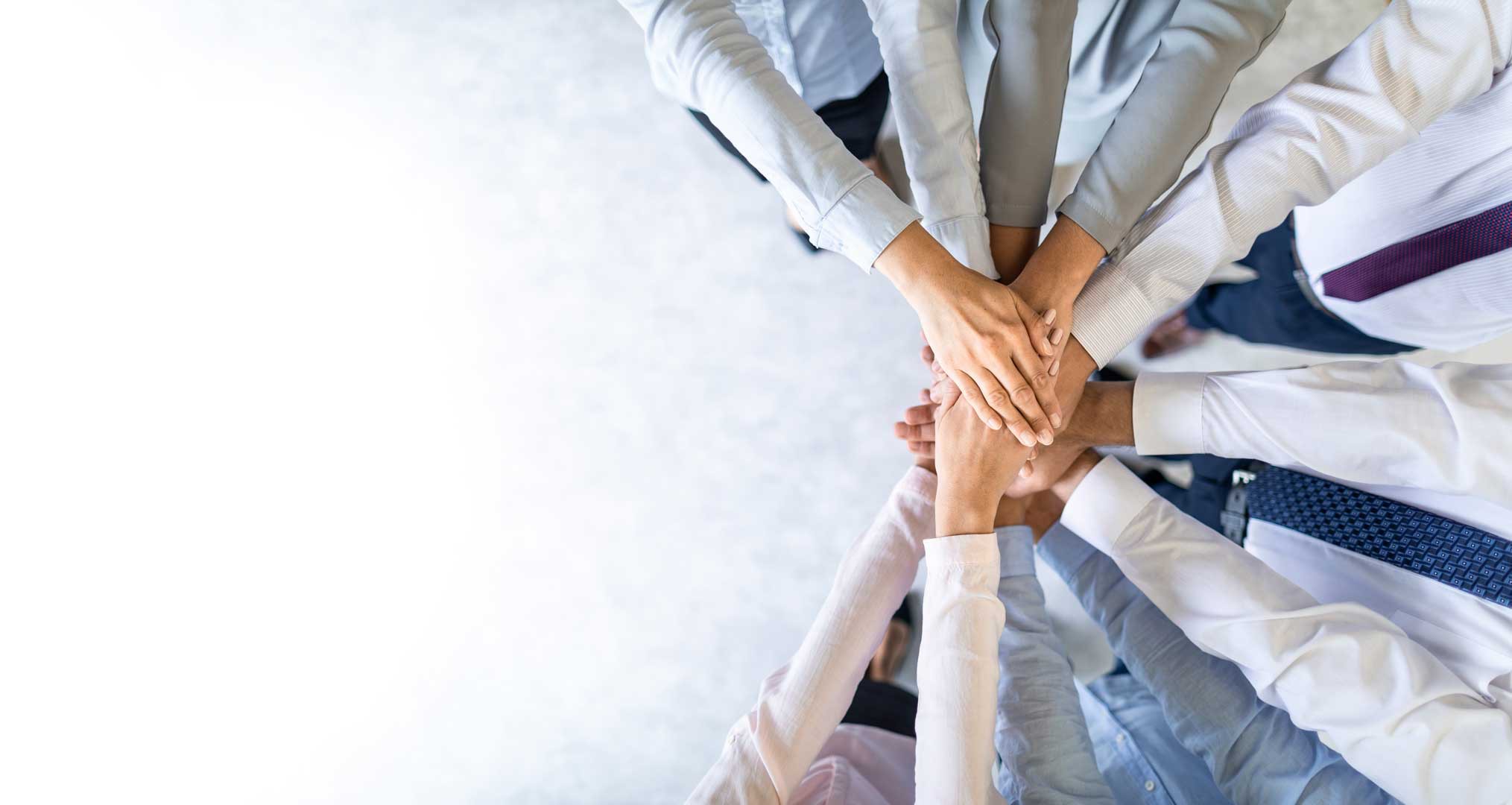 Mehrere Menschen legen ihre Hände übereinander als Zeichen von Teamwork.
